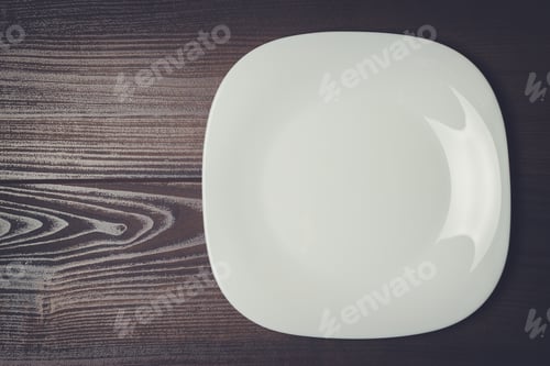 Vista previa: plato cuadrado blanco sobre la mesa de madera marrón