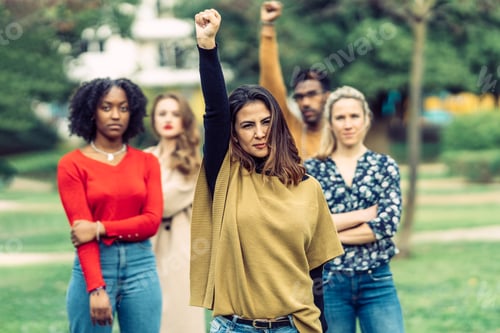 Preview: woman with latin features raises her fist protesting inequality between men and women