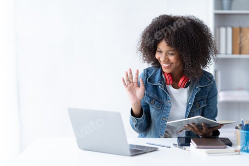 Preview: Focused young African female college student working on a laptop on living room.