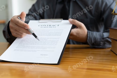 Preview: Lawyer working in a law office reading agreement contract documents and signing.