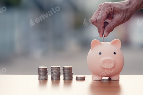 Preview: Hands holding coin put in the piggy bank with coins stacks on wood table