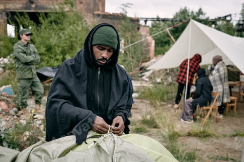 Man Assembling Tent in a Post-Conflict Environment