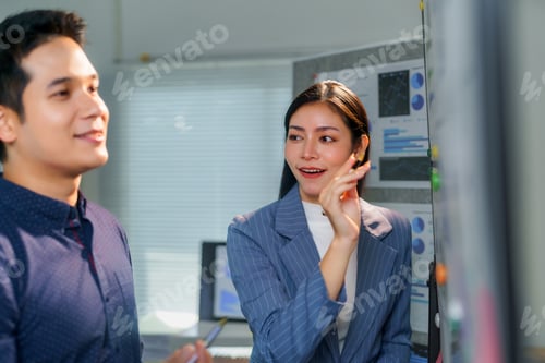 Preview: Asian businesspeople discussing and brainstorming using sticky notes on glass board in the office