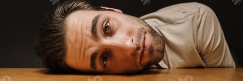 Preview: Upset sad man laying his head on a table indoors