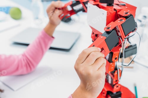 Preview: partial view of schoolkid playing with robot model during STEM lesson