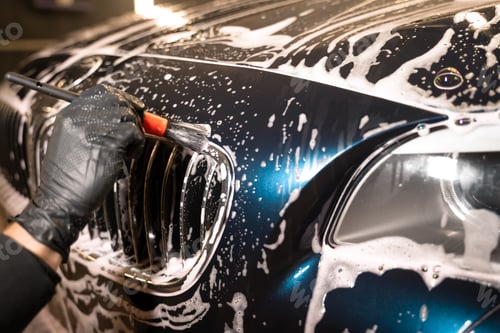 Preview: Detailed car wash. Detailing center worker cleans car's radiator grill with brush