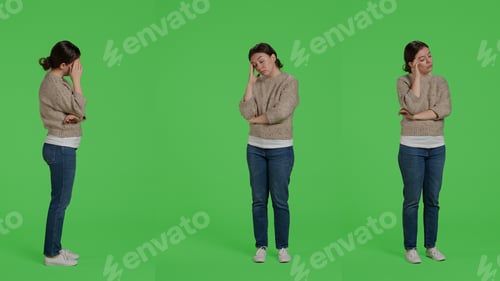 Preview: Female model in pain suffering from headache over greenscreen backdrop