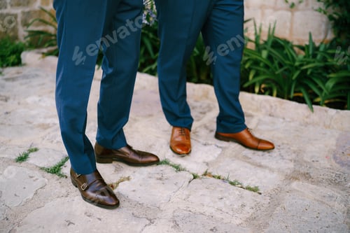 Preview: The legs of two men standing on a cobbled road, close-up. The groom and his best man during the