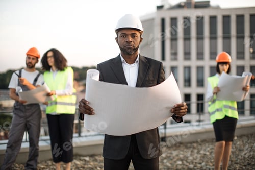 Preview: Investor posing at camera while colleagues inspecting object