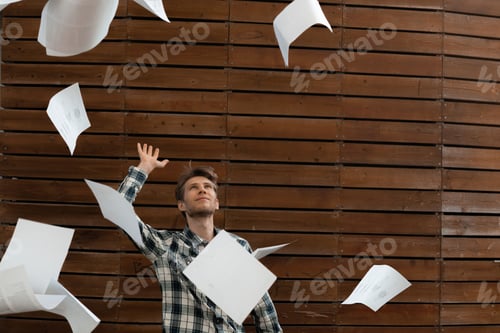Preview: young stressed man throw crumpled paper files in the air, freedom concepts