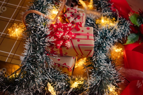Preview: Closeup on Christmas gift boxes in a shopping bag, paper's rools and decorations on red