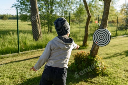 Preview: Child Playing Darts Outdoors in a Grassy Yard