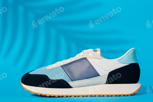 Preview: Trendy youth shoes on blue background with plant shadow
