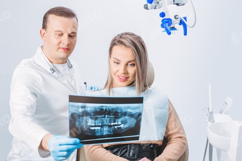 Preview: doctor shows a x-ray picture to patient. Closeup. Doctor hands in gloves hold x-ray picture