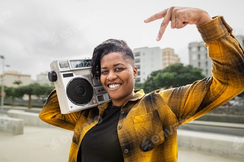 Preview: Happy African woman having fun listening to music with vintage boombox stereo