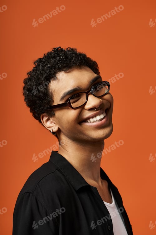 Preview: Charming Vision: Smiling Young Man in Glasses on Vibrant Orange