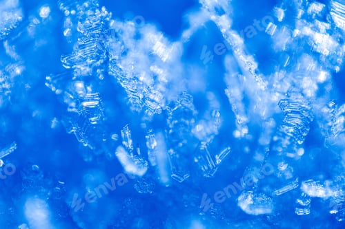 Preview: Close up of snow crystals illuminated by blue sunlight. Winter background. Macro of real snowflake