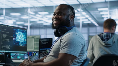 Vista previa: Ingeniero feliz riéndose de la broma de un compañero de trabajo mientras trabaja en una instalación de IA de alta tecnología
