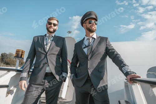 Preview: Two pilots in sunglasses standing on aircraft stairs before flight in airport