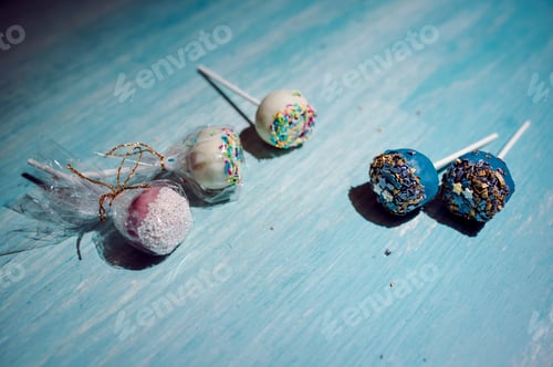 Preview: High angle shot of deliciously decorated pop cakes on a blue surface