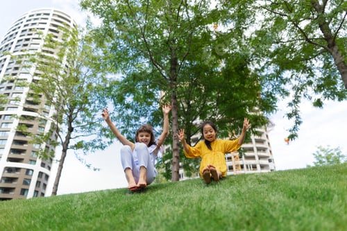 Preview: Asian girl trying to skateboarding with her friend in city park, active kids concept.