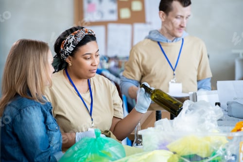 Preview: Two young female volunteers looking at empty clean wine bottle