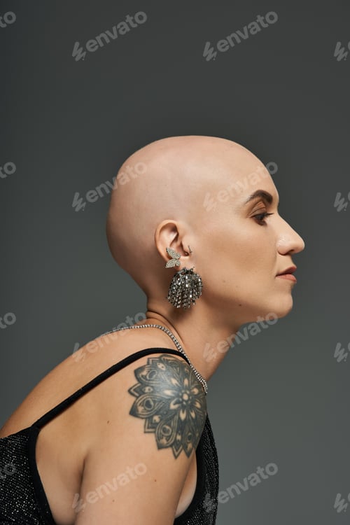 Preview: Bald young woman with alopecia elegantly showcases her tattoos in a striking portrait