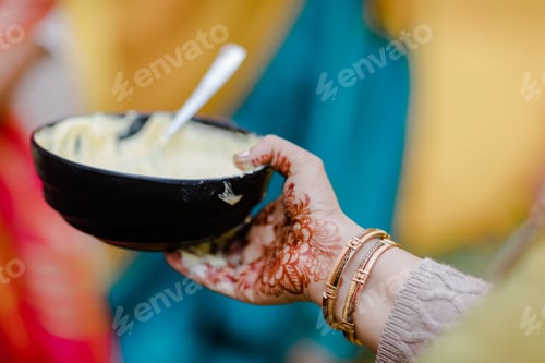 Preview: Female hand with hanna tattoos holding a turmeric paste to apply to the bride's and groom's body
