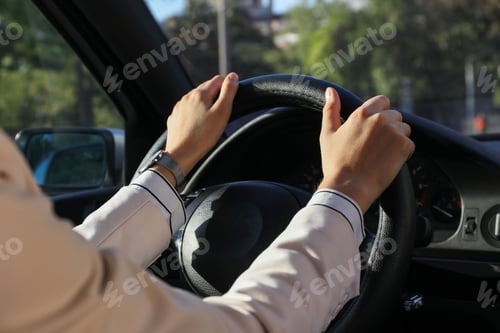 Preview: Woman holding steering wheel while driving car, closeup