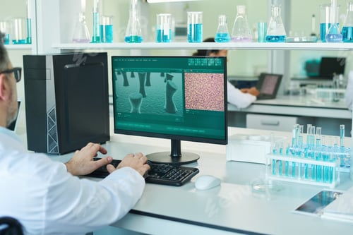 Preview: Arms of mature scientist carrying out clinical experiment while sitting by desk
