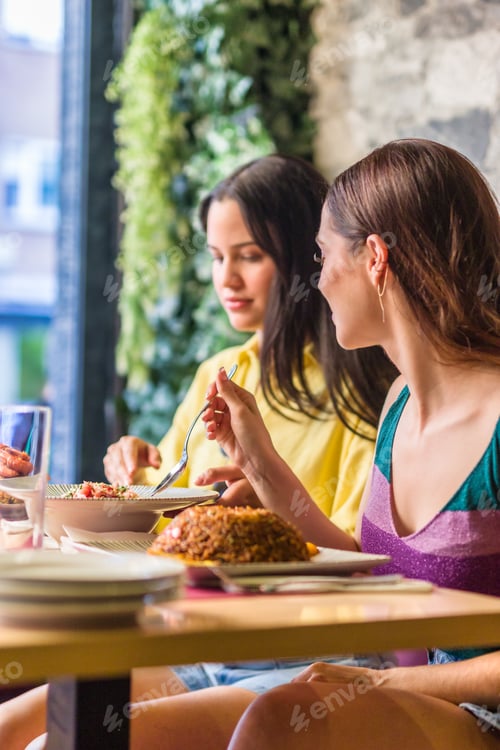 Preview: Latinx female friends together eating happy in a Ecuadorian food restaurant. Traditional meal
