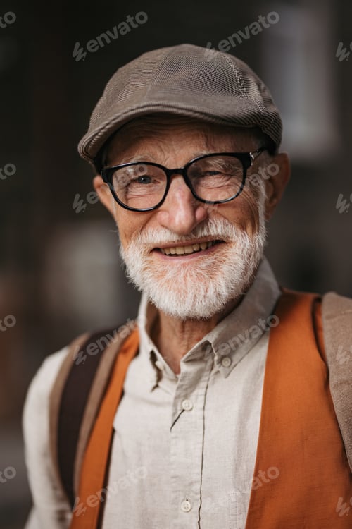 Preview: Studio portrait of a senior man with glasses and a beret on his head.