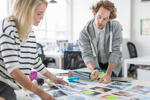 Preview: Young colleagues discussing photographs in meeting in creative office