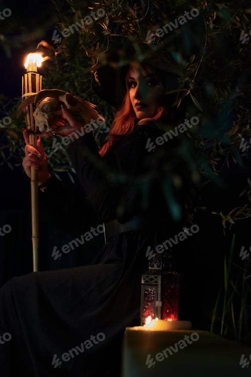 Preview: Woman disguised as a witch holding a flaming torch and a skull
