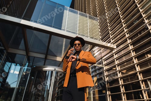 Preview: Mixed race business man wearing suit talking on mobile phone device outside office building