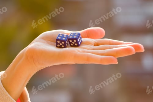 Preview: Dice 4 4 in the female hand, sunset background. Gambling devices