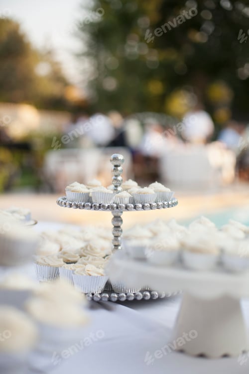 Preview: A table laid for a banquet or a wedding breakfast. White table cloth, cake stand, and table setting.
