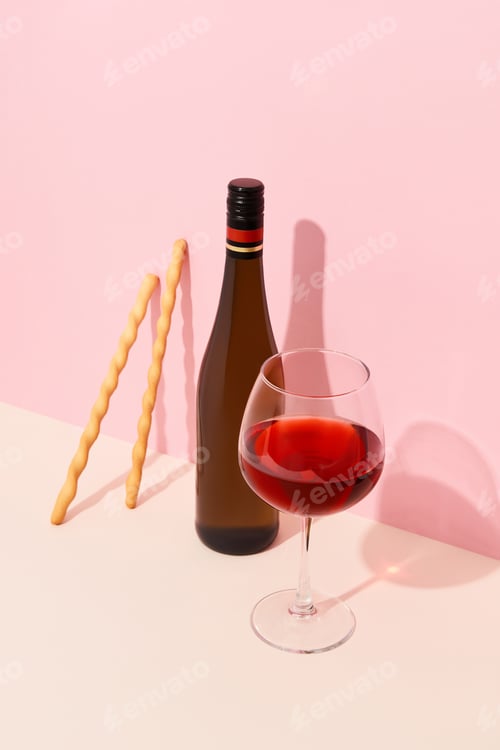 Preview: Bottle, glass of wine and grissini on red background with deep shadows. Mock up drink