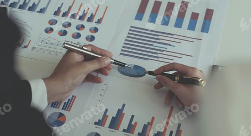 Preview: Close-up of two women's hands pointing to a turnover chart while talking on a wooden table in the