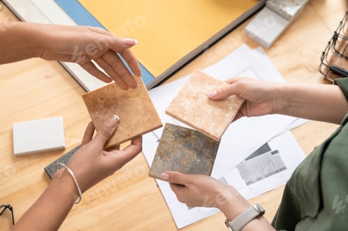 Preview: Hands of two young female designers comparing samples of marble tiles