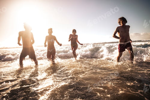 Preview: Group of happy young millennial people play and run in the sea waves water together - friends