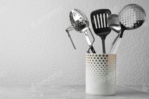 Preview: Set of kitchen utensils in stand on stone table near light wall. Space for text