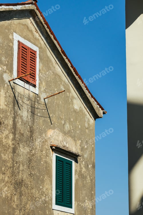 Preview: The Sunlit Facade: Croatian Old House with Colorful Shutters and Contrasting Shadows