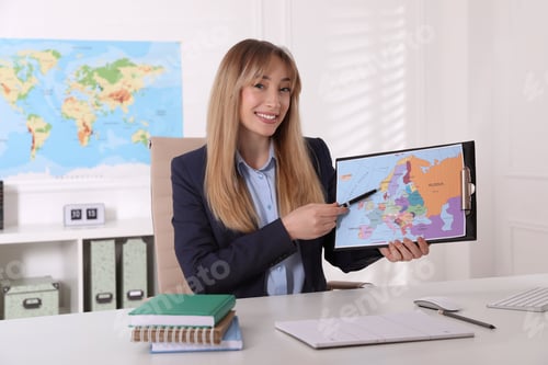 Preview: Happy manager showing map at desk in travel agency