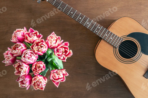 Preview: Bouquet of pink tulips and acoustic guitar on a wooden background, top view.