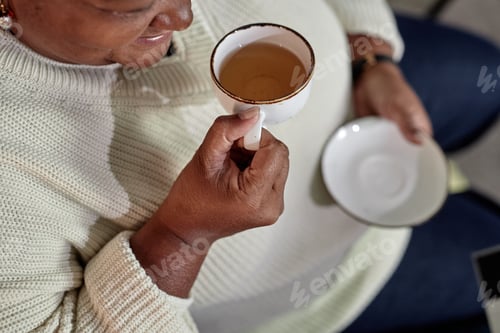Preview: Hand of Elderly Black Woman Drinking Tea from Ceramic Cup at Home