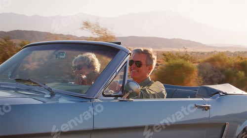 Preview: Side View Of Senior Couple On Road Trip Driving In Classic Convertible Car Along Country Road