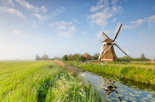 Preview: Dutch windmill by river over blue sky