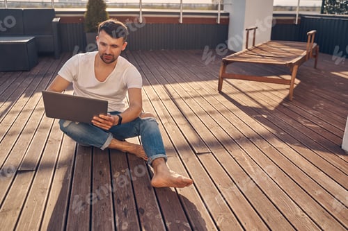 Preview: Attractive Caucasian man sitting outside on the floor