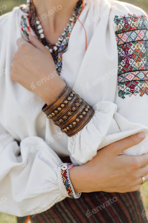 Preview: Young woman in traditional national embroidered shirt and skirt on nature at sunset.